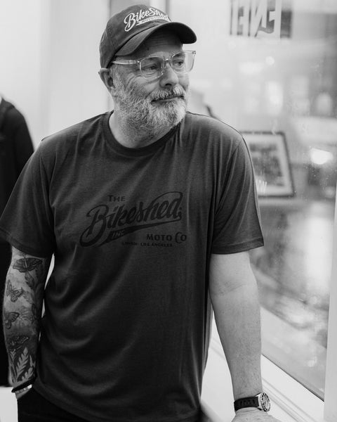Model wearing Bike Shed Moto Co Inc T-Shirt Green in a white shop