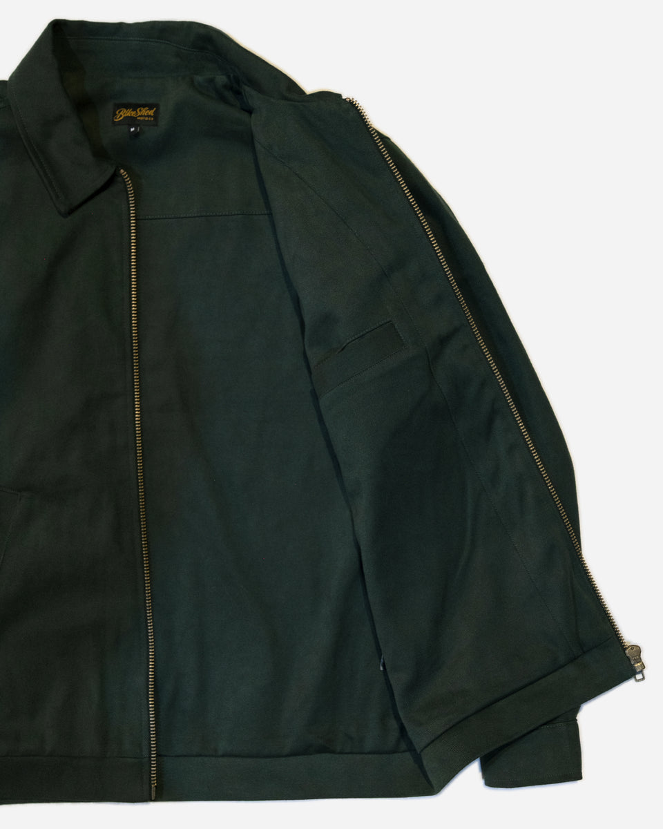 Dark green motorcycle jacket with a Bike Shed Moto Co brand logo on a white background